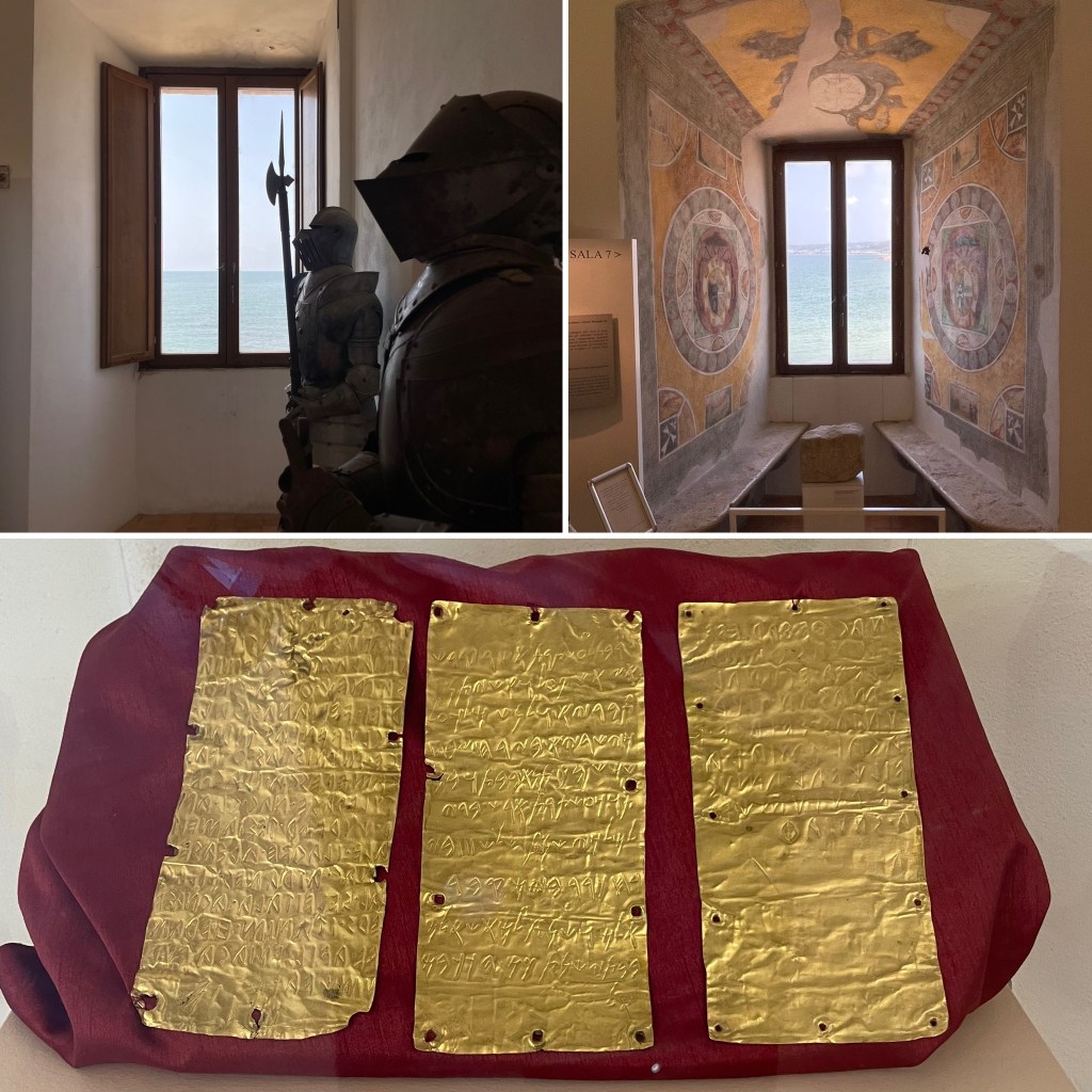 A triptych. Top row has 2 photos, on the left, 2 suits of armor in front of a window looking out to the sea from inside the castle, on the right, an alcover with murals surrounding a window looking out to the sea from inside the castle. On the bottom, 3 gold sheets with ancient engravings on there on a burgundy cloth.