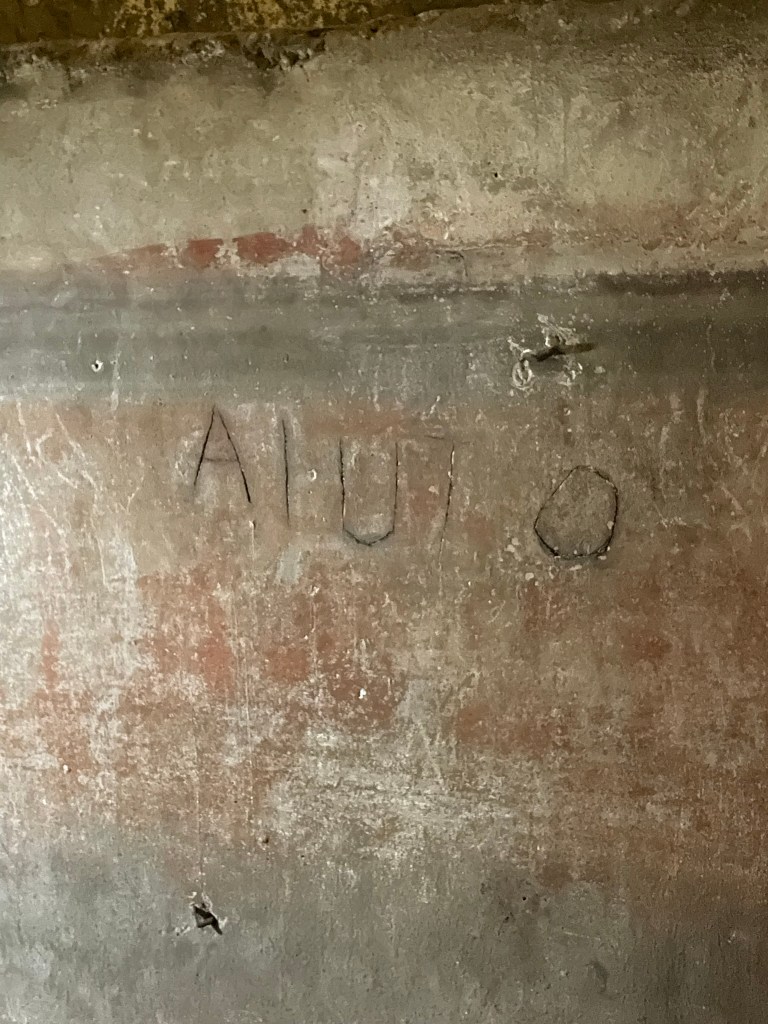 A photo of the word "aiuto" -- which means "help" in Italian -- carved into the tufa, put there by someone using the space as a bomb shelter during WWI. 
